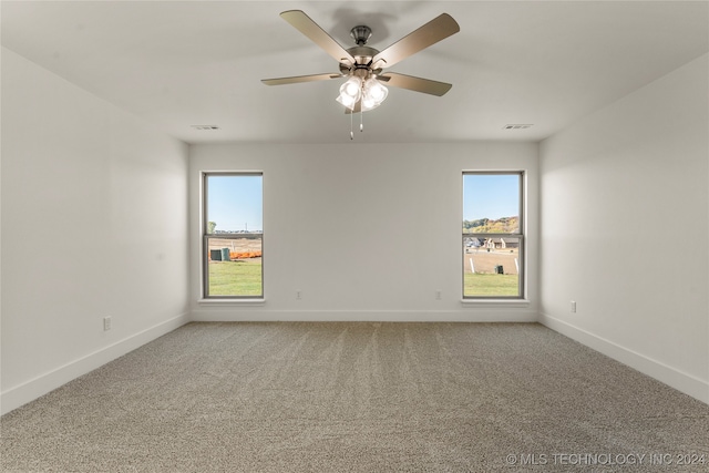 carpeted spare room featuring a healthy amount of sunlight and ceiling fan