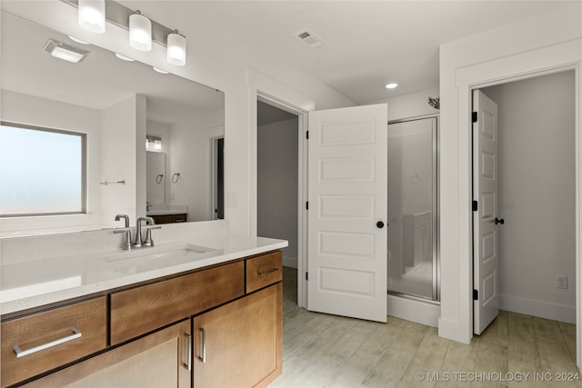 bathroom with vanity, wood-type flooring, and a shower with door