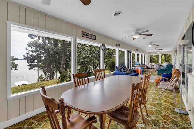 sunroom featuring a water view and ceiling fan