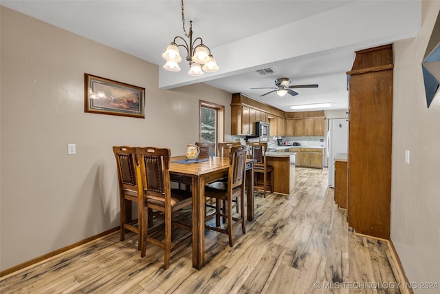 dining room with ceiling fan with notable chandelier and light hardwood / wood-style floors