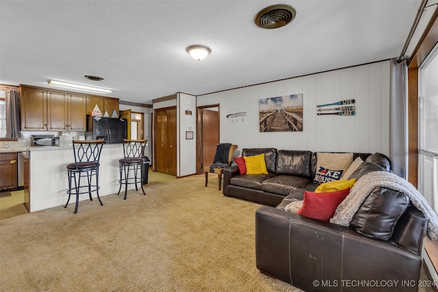 living room featuring wooden walls, a textured ceiling, light colored carpet, and crown molding