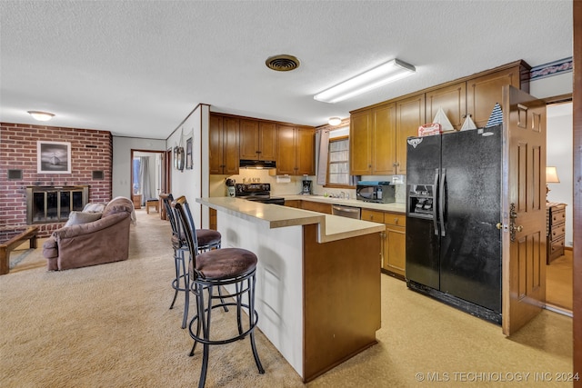 kitchen with a kitchen breakfast bar, black appliances, a textured ceiling, and light carpet