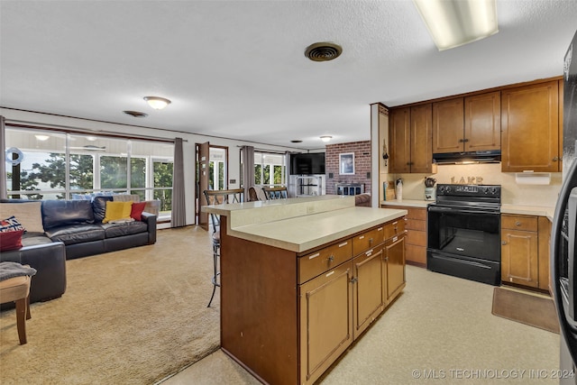 kitchen with a textured ceiling, a center island, black electric range, a breakfast bar area, and light carpet