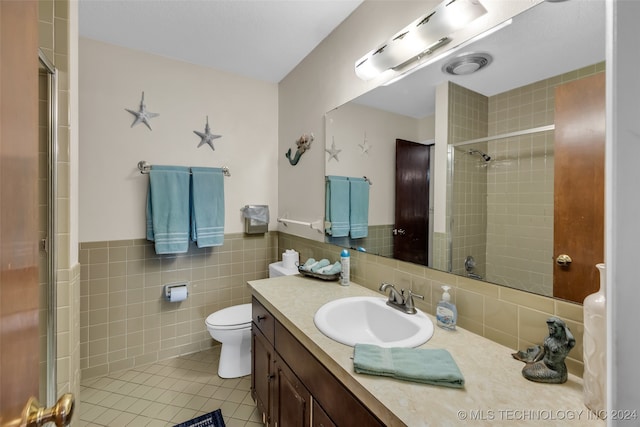 bathroom featuring a tile shower, tile walls, tile patterned floors, vanity, and toilet