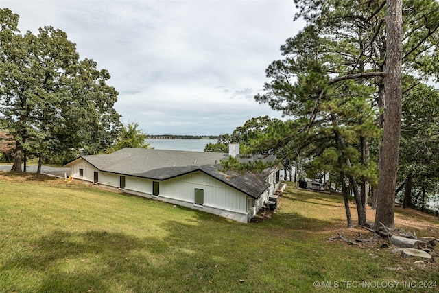 view of side of home featuring a lawn and a water view