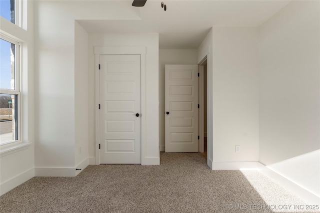 unfurnished bedroom with ceiling fan, carpet flooring, and multiple windows