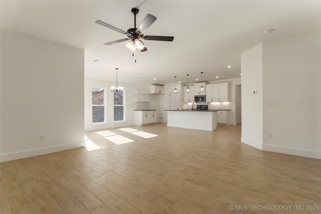 unfurnished living room with light wood-type flooring, sink, and ceiling fan with notable chandelier