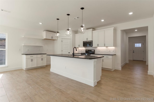 kitchen with white cabinetry, range, and a center island with sink