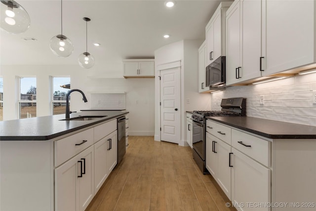 kitchen featuring black gas range oven, a kitchen island with sink, decorative light fixtures, dishwasher, and white cabinets