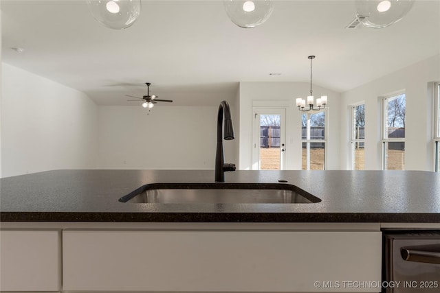 kitchen featuring vaulted ceiling, pendant lighting, sink, white cabinetry, and ceiling fan with notable chandelier