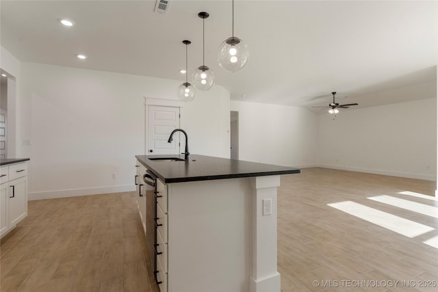 kitchen featuring ceiling fan, a center island with sink, sink, hanging light fixtures, and white cabinets