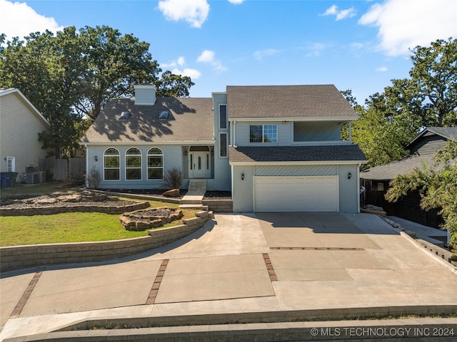 view of front of property featuring a garage, central air condition unit, and a front lawn