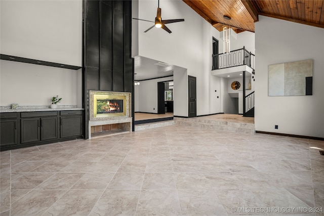 unfurnished living room with wood ceiling, a large fireplace, ceiling fan, and high vaulted ceiling