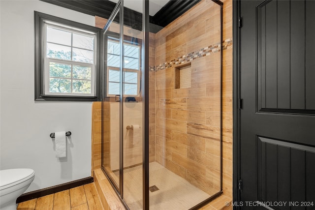 bathroom with hardwood / wood-style flooring, a shower with shower door, and toilet