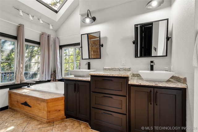 bathroom featuring vanity, a bathing tub, tile patterned flooring, and lofted ceiling with skylight