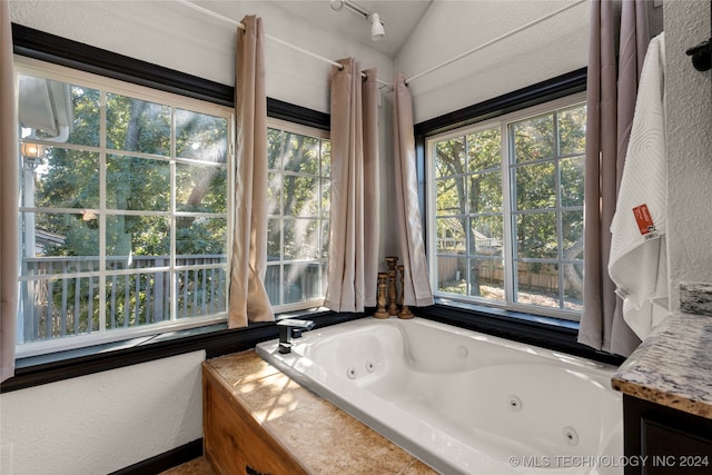 bathroom featuring vaulted ceiling and a relaxing tiled tub