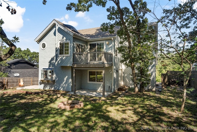 rear view of property with a balcony, a yard, a patio area, and an outdoor fire pit