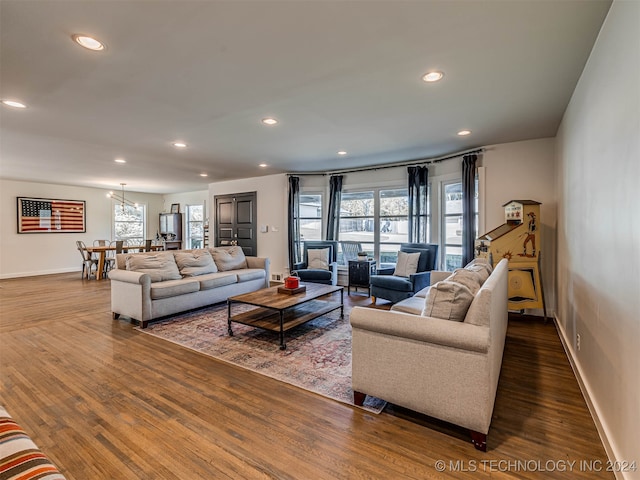 living room with a notable chandelier, a healthy amount of sunlight, and dark hardwood / wood-style flooring