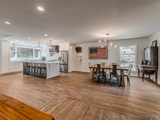 dining space featuring wood-type flooring, a notable chandelier, and sink