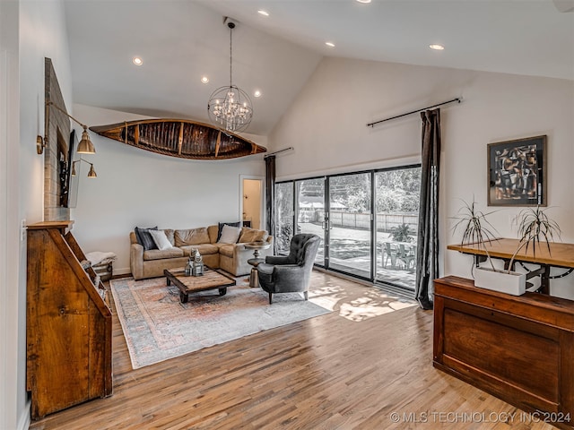 living room with light wood-type flooring, a chandelier, and high vaulted ceiling