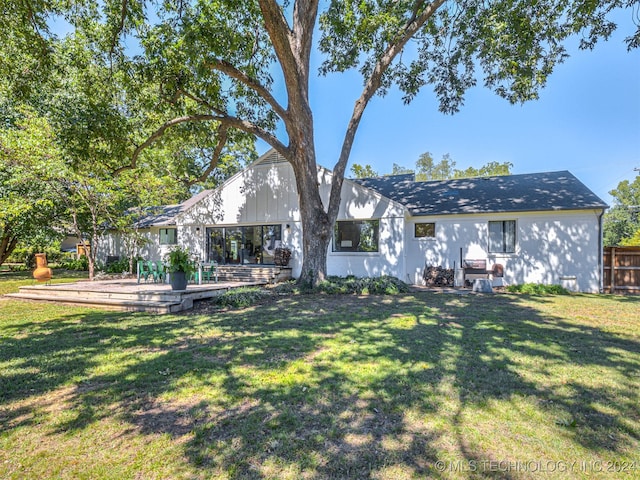 back of property featuring a deck and a yard