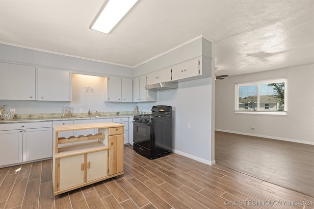 kitchen featuring sink, black gas range oven, white cabinetry, dark hardwood / wood-style floors, and crown molding