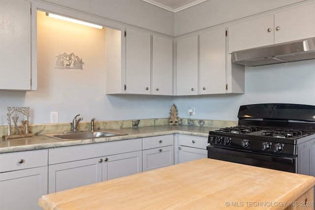 kitchen featuring ornamental molding, sink, black gas range oven, and white cabinetry