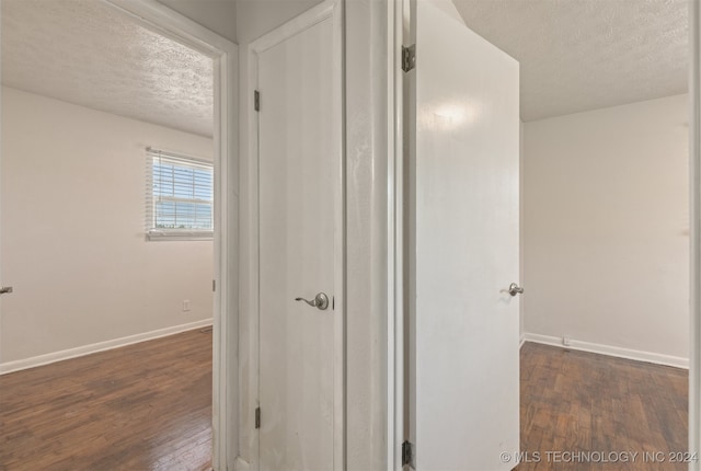 hall with a textured ceiling and dark wood-type flooring