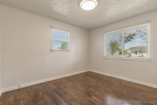 unfurnished room featuring a textured ceiling and dark hardwood / wood-style flooring