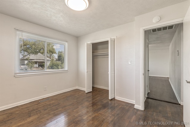 unfurnished bedroom with a textured ceiling, a closet, and dark wood-type flooring