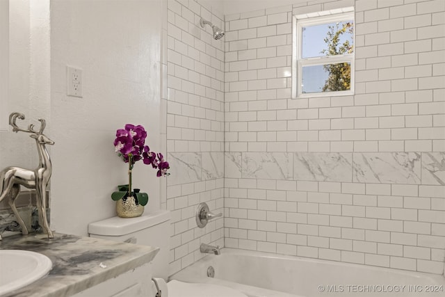 full bathroom featuring tiled shower / bath combo, vanity, and toilet