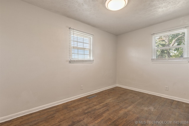 empty room featuring a textured ceiling and dark wood-type flooring