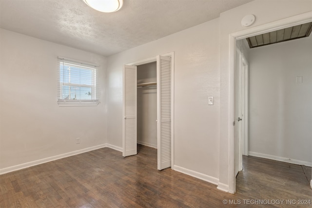 unfurnished bedroom featuring a textured ceiling, dark hardwood / wood-style flooring, and a closet