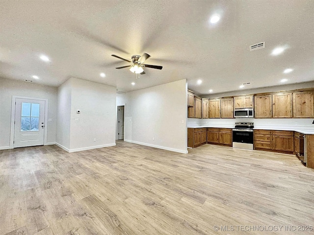 kitchen with ceiling fan, stainless steel appliances, a textured ceiling, and light wood-type flooring