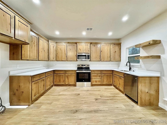 kitchen with sink, light wood-type flooring, and appliances with stainless steel finishes