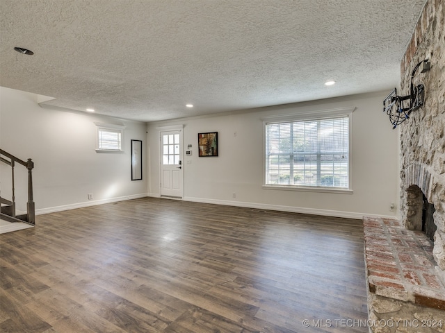 unfurnished living room with a textured ceiling, plenty of natural light, and dark hardwood / wood-style flooring