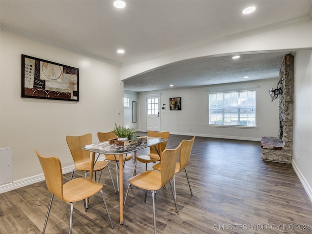 dining room with ornamental molding, a textured ceiling, hardwood / wood-style flooring, and a healthy amount of sunlight