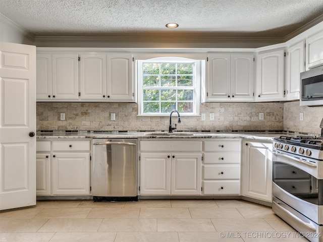 kitchen with appliances with stainless steel finishes, white cabinetry, sink, and tasteful backsplash