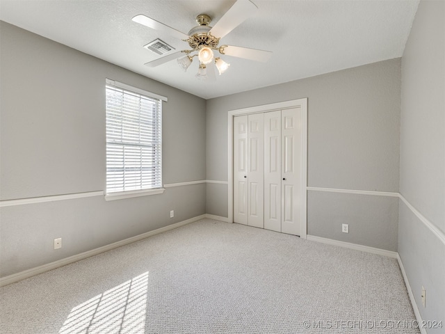 unfurnished bedroom with carpet, a closet, and ceiling fan