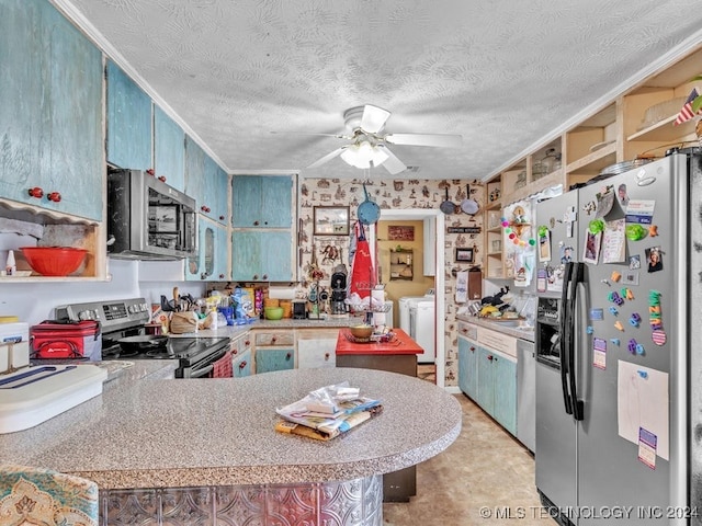 kitchen with ceiling fan, kitchen peninsula, washing machine and clothes dryer, a textured ceiling, and appliances with stainless steel finishes