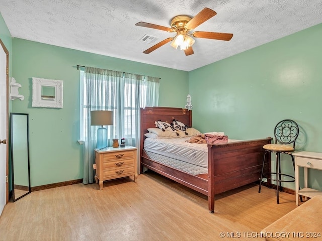 bedroom with wood-type flooring, ceiling fan, and a textured ceiling