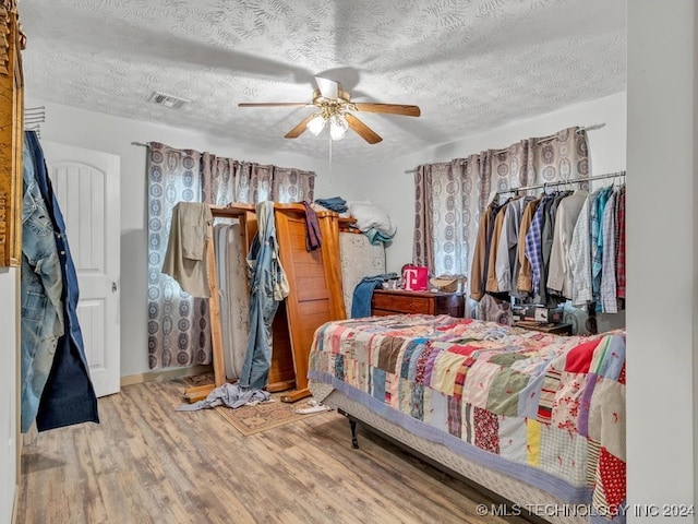 bedroom featuring ceiling fan, hardwood / wood-style flooring, and a textured ceiling