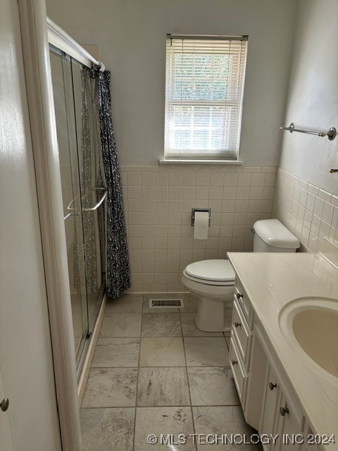 bathroom with walk in shower, tile walls, vanity, and toilet