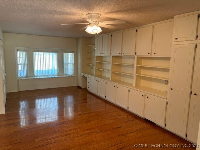 unfurnished living room with a textured ceiling, dark hardwood / wood-style floors, and ceiling fan