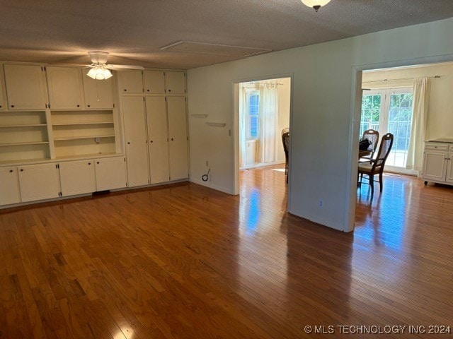 unfurnished living room featuring ceiling fan, a textured ceiling, and hardwood / wood-style floors