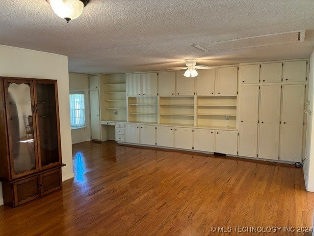 unfurnished living room featuring wood-type flooring, a textured ceiling, and ceiling fan