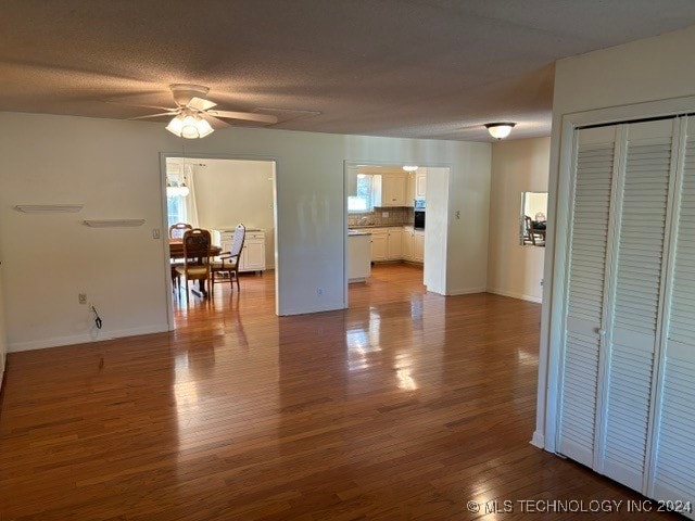 living room featuring ceiling fan, hardwood / wood-style flooring, and a textured ceiling