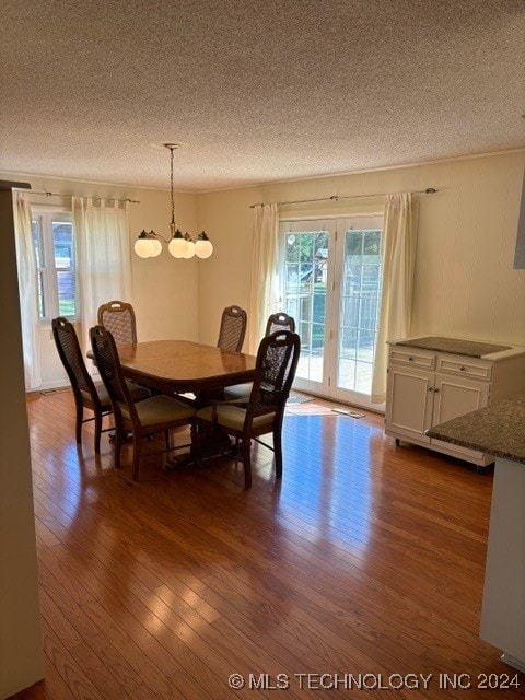 dining area with a textured ceiling, hardwood / wood-style flooring, and french doors