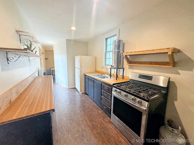 kitchen featuring white refrigerator, stainless steel gas stove, dark hardwood / wood-style floors, and sink