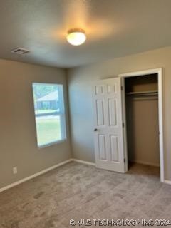 unfurnished bedroom with light carpet and a closet